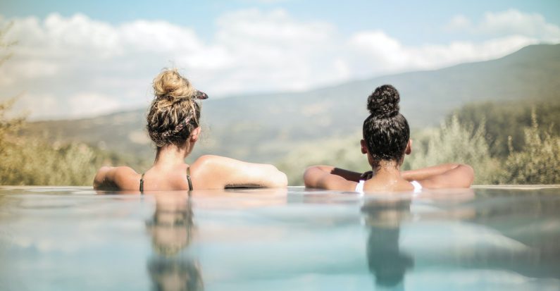 deux femmes accoudées au bord d'une piscine