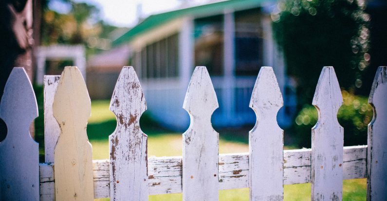 Le jardin d'une maison avec une barrière blanche devant