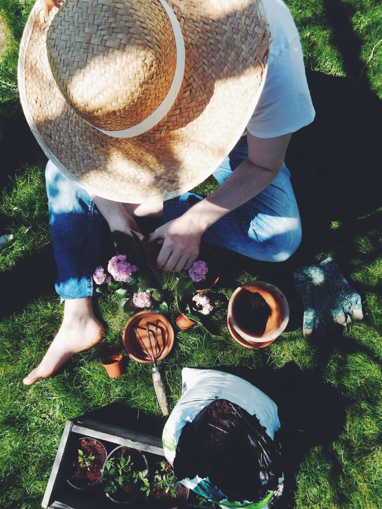 Femme qui jardine en extérieur et plante dans des pots