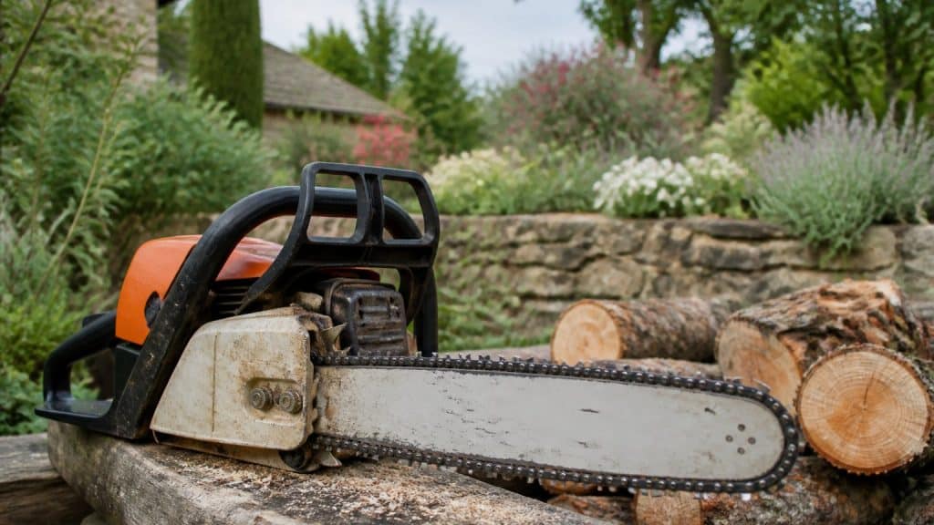 Gros plan sur la chaîne et le guide d'une tronçonneuse posée sur une bûche de bois dans un jardin