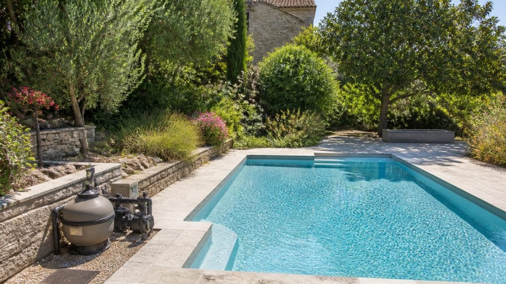 Piscine de jardin avec équipement de filtration visible au bord du bassin