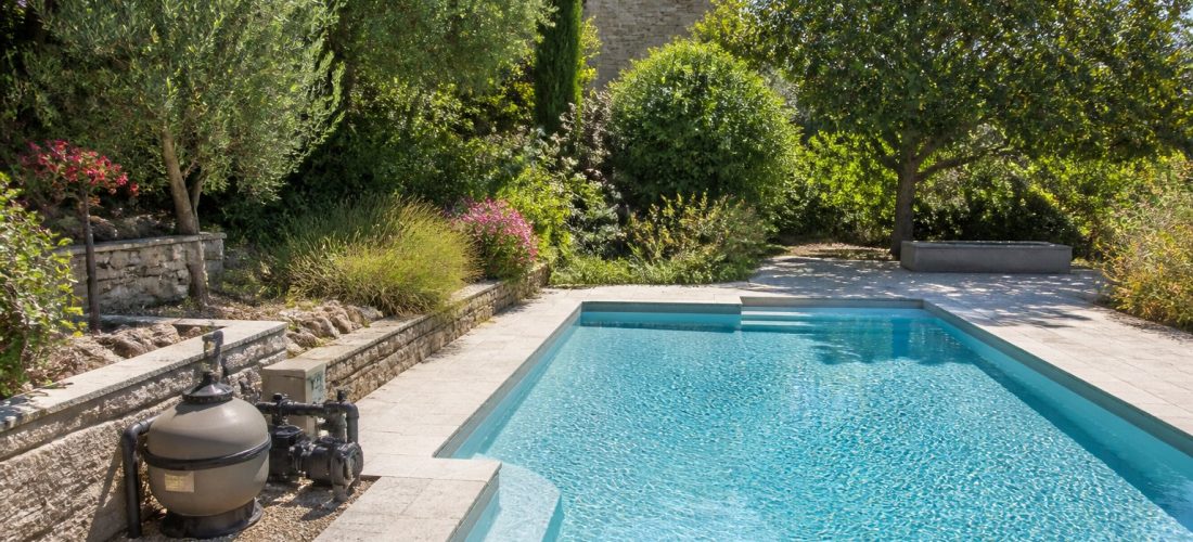 Piscine de jardin avec équipement de filtration visible au bord du bassin